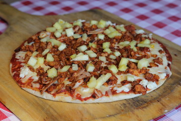 A delectable pizza crafted with pulled al pastor pork, pineapple chunks, and melty cheese, set against a backdrop of vibrant colors and textures for pizza lovers to savor.