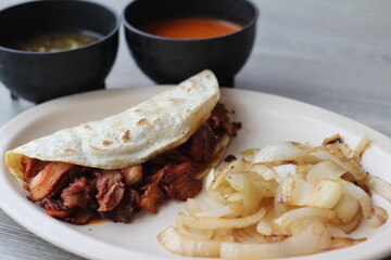 Authentic al pastor taco made with flavorful meats, served with sautéed onions and vibrant sauces, representing the essence of traditional street food in a colorful presentation.