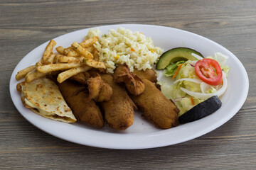 A hearty meal of crispy fried fish paired with rice, fries, and a fresh salad, showcasing a delightful combination of flavors and textures for seafood enthusiasts.