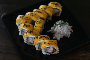 An elegant sushi roll made with shrimp and topped with fresh mango, beautifully arranged,...