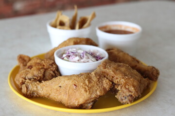 This image showcases a plate of crispy fried chicken served with coleslaw and dipping sauces, highlighting the deliciousness and comfort of classic comfort food.