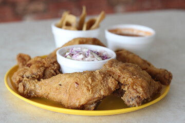 A plate of crispy fried chicken served with coleslaw and dipping sauce offers a hearty and comforting meal, perfect for indulging in classic comfort food cravings.