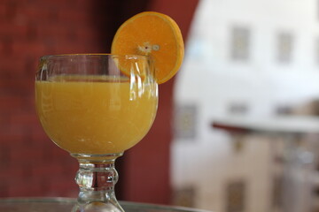 A refreshing orange drink served in a sophisticated glass, garnished with a slice of orange, perfect for a sunny day, evoking feelings of relaxation and hydration.