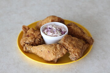 Mouthwatering plate of crispy fried chicken served with a side of refreshing coleslaw, capturing...