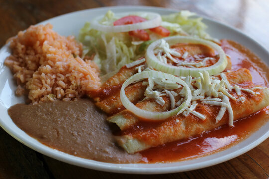 A flavorful plate of entomatadas accompanied by rice and beans, exemplifying the heart of Mexican cuisine and the warmth of shared meals among loved ones.