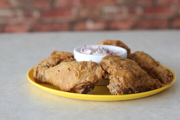 A tantalizing plate of crispy fried chicken pieces, beautifully presented with a side of creamy dipping sauce, offering comfort food at its best with an inviting appearance.