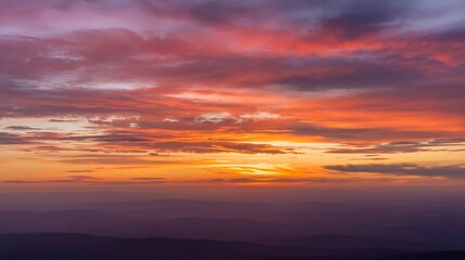Fototapeta premium Vibrant sunset over distant mountains with a colorful and dynamic sky