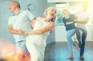 Group of multinational sports aged people rehearsing social dance in dance hall