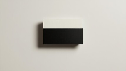 Two-tone box, ivory above dark, rests on a light tan surface, casting soft shadows