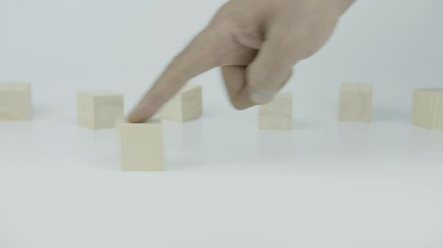 A finger pushes a wooden block with the number eight next to another block on a white background, symbolizing steady progress, numeric order, or continuation within a clean and minimal scene