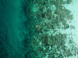 Stunning aerial view of a pristine coastline where crystal-clear turquoise water gently washes over a vibrant coral reef, Ko Kradan, Thailand