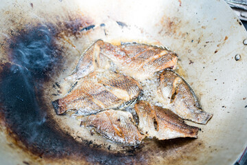 Frying Tilapia fish in cooking pan at Thai household