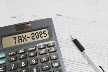 Text Tax 2025 on the calculator and taxes documents. Business and Annual tax concept.
