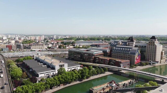 Drone shot approaching Grands Moulins de Pantin with canal and Paris skyline in view - France