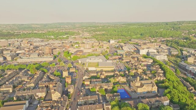 Huddersfield city centre revealing Queensgate Market and nearby streets framed by Victorian buildings, parking areas, and distant green hills under soft morning light drone static shot