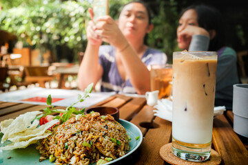 Asian family activities during lunch time at an outdoor restaurant with traditional fried fries, iced coffee and iced tea served on the table