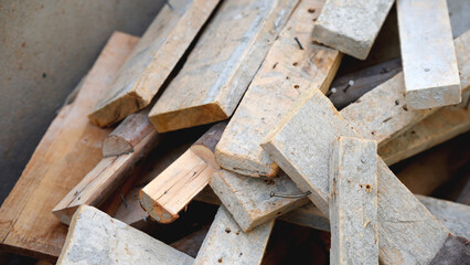 Piled wooden planks in a mixed arrangement, showing various shapes and textures.