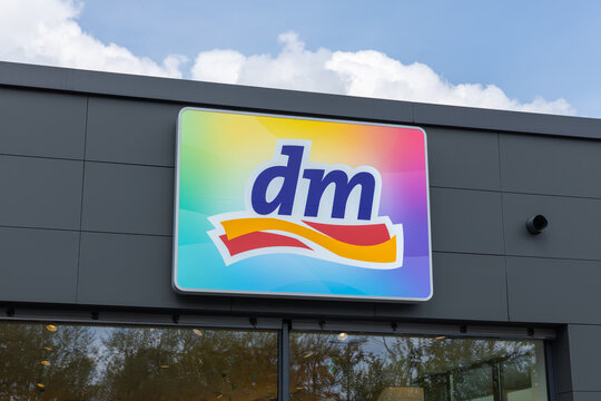 A colorful dm (drogerie markt) drugstore sign with its distinctive logo against a backdrop of a gray building and cloudy sky. Kleve, Germany. 22 April 2025.