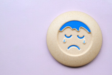 A toy with a symbol of a crying person. Concept of depression which is very common in today's competitive.