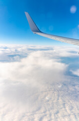 View from the airplane window at a beautiful cloudy sky and the airplane wing