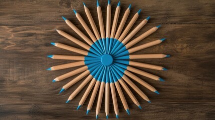 Colorful Arrangement of Pencils Radiating from Central Blue Circle on Wooden Surface