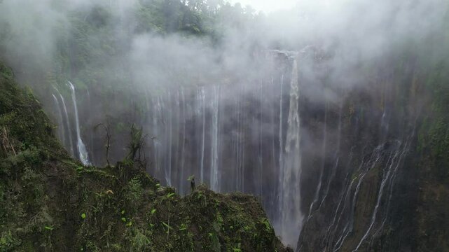 Tumpak Sewu waterfall in mystique foggy atmosphere on Java Island, Indonesia.