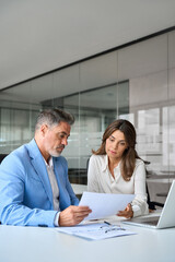 Two busy older executives discussing financial documents at meeting. Professionals team talking...