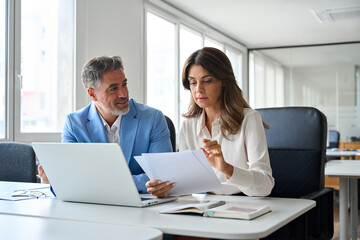 Two busy professional executives team working on laptop discussing financial documents at meeting....