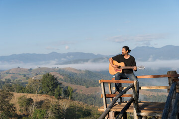 Man Playing Guitar on Mountain Viewpoint with Scenic Landscape