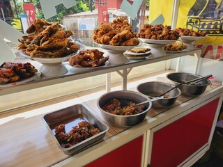 Display of various fried and cooked foods on restaurant shelves.