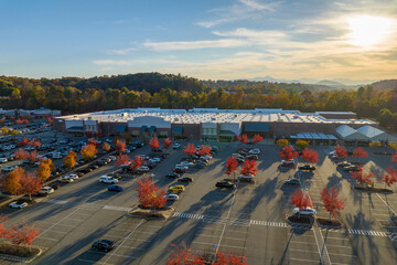 Aerial view of large parking lot in front of rgocery store with many parked colorful cars. Carpark...
