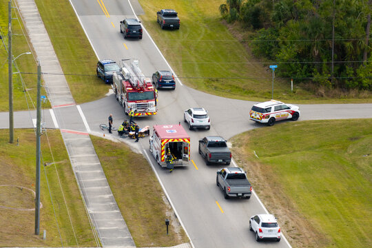 Car crash with first responders helping cyclist who was hit by car at accident site on American street. Vehicle and pedestrian collision on road in USA
