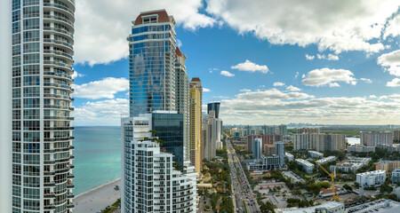 Obraz premium View from above of luxurious highrise hotels and condos on Atlantic ocean shore in Sunny Isles Beach city. American tourism infrastructure in southern Florida