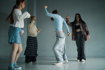 Group of diverse young women enjoying dancing session in minimalistic room. Casual attire and joyful expressions capturing essence of modern youth culture