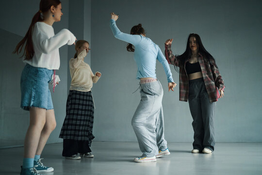 Group of diverse young women enjoying dancing session in minimalistic room. Casual attire and joyful expressions capturing essence of modern youth culture