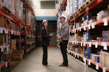 Distribution warehouse manager and client businesswoman using digital tablet checking inventory storage on shelf. Storehouse business worker and logistic engineer standing together at storage service