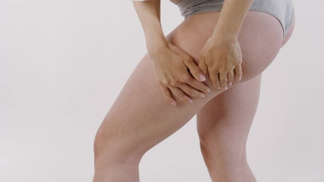 Profile shot of a woman applying lotion to her thigh with smooth, downward strokes. Calm and focused skincare moment.