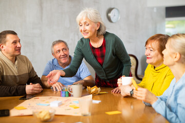 Group of positive older people playing tabletop game