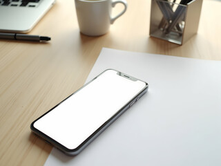 Aesthetic workspace featuring a modern frameless mobile phone with a blank display screen surrounded by work related items like a laptop and mug
