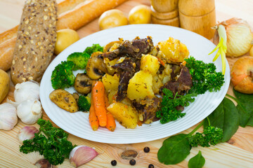 Delicious roast with beef, mushrooms and vegetables served with herbs on plate