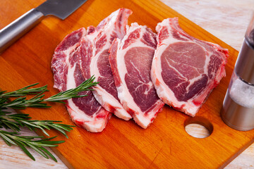 Fresh raw pork chop steak on wooden background with herbs