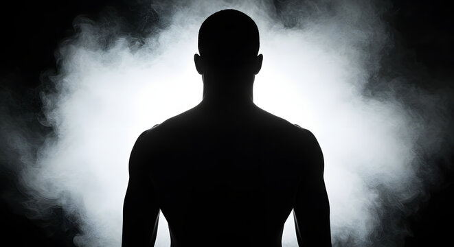 A naked dude stands with his back to the camera, silhouetted against a smoke background. He's got short, dark hair and a buff build, with his shoulders and upper back