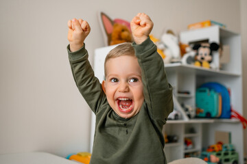 Excited toddler celebrating with enthusiasm in a playful indoor setting