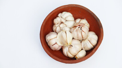 Close up of raw garlics on wooden bowl. top view. isolated white