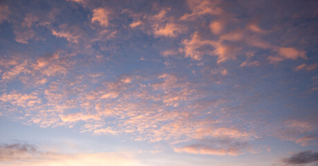 sunset sky background with light pink fleecy clouds, panorama