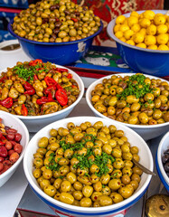 A colorful display of Moroccan olives in bowls with preserved lemons and herbs