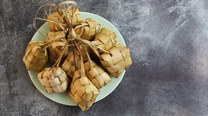 Close up view of Ketupat, an Indonesian traditional cuisine very popular during Hari Raya Idul Fitri served on a wooden table. This is made of the white rice, usually served with opor ayam on Ied day.