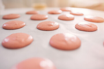 Close-up of pink macaron batter on a baking sheet during preparation