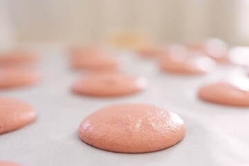 Close-up of pink macarons batter resting on a baking sheet