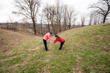 Two friends enjoy a moment of connection while stretching in a serene landscape adorned with bare...